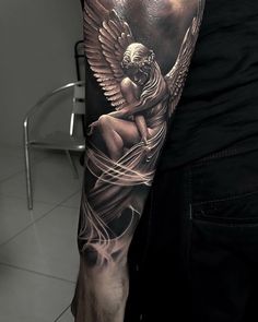 a man with a black and white tattoo on his arm holding an angel in the air