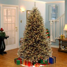 a decorated christmas tree in the middle of a living room with blue walls and wooden floors