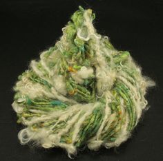 a green and white yarn ball sitting on top of a black surface with lots of thread