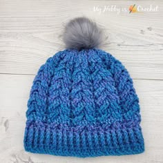 a blue knitted hat with a grey pom - pom