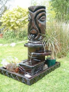 a water fountain in the shape of a totema with plants growing out of it