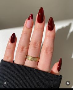 a woman's hand with red nail polish and gold ring on her finger, wearing a black sweater