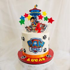 a paw patrol birthday cake on top of a white tablecloth with stars around it