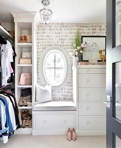 a closet with white drawers and shelves filled with clothes, shoes and other items next to a round window