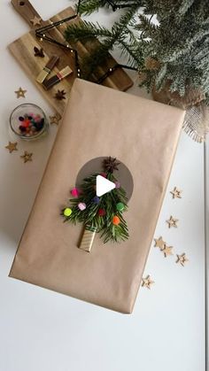 a present wrapped in brown paper with a christmas wreath on it next to a tree