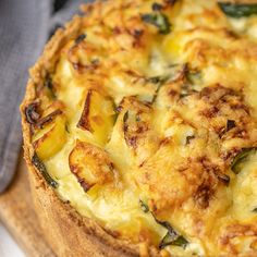 a quiche with cheese and spinach on a cutting board