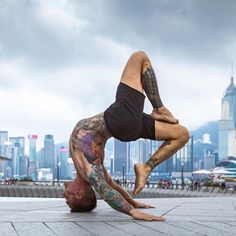 a man doing a handstand on the ground in front of a cityscape