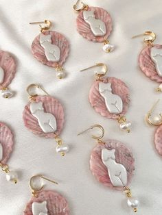 pink and white shell earrings with pearls on the bottom are laying on a white sheet