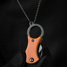 a person holding a small orange and black object on a chain with a ball chain attached to it