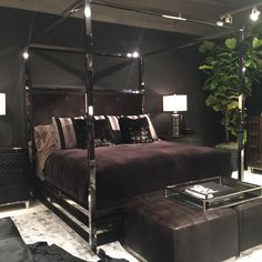 a bedroom with a canopy bed, ottoman and mirror table in the corner next to it