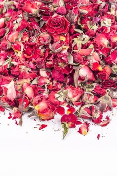 a pile of dried red roses sitting on top of a white table