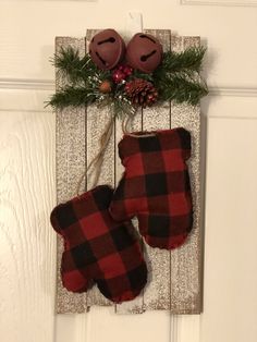 two mittens hanging on a door hanger decorated with pine cones and plaid fabric