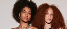 three women with curly hair standing next to each other