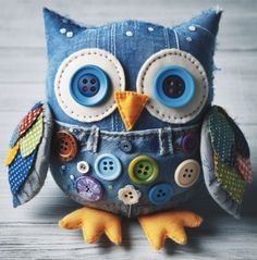 an owl stuffed animal with buttons on it's eyes sitting on a wooden surface