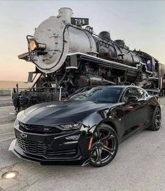 a chevrolet camaro is parked next to a train