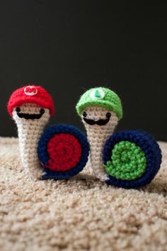 two crocheted toy mushrooms sitting on top of a carpet next to each other