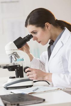 a woman looking through a microscope at something