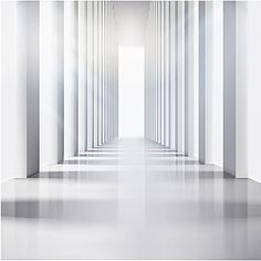 an empty white room with columns and light at the end