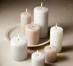 five white candles sitting on top of a plate