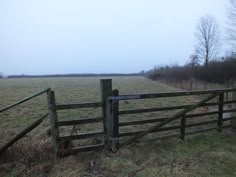 a wooden gate in the middle of a field