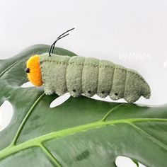 a caterpillar is sitting on top of a green leaf