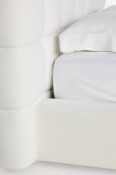 a bed with white linens and pillows on top of it, against a white background