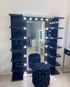 a large black lighted mirror with stools in front of it and shelves on the wall