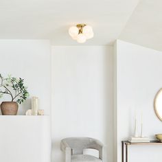 a living room with white walls and a round mirror on the wall next to a chair