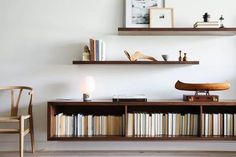 two shelves with books and other items on them in a room that has white walls