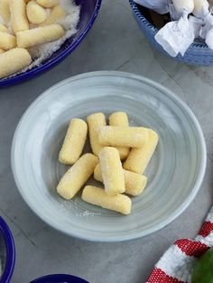 small pieces of food are in a bowl next to other bowls and utensils