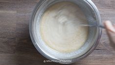 someone mixing batter in a bowl on top of a wooden table