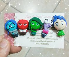 a person holding up a business card with small cartoon characters on it's front