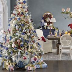 a decorated christmas tree in a living room with blue and white ornaments on the top