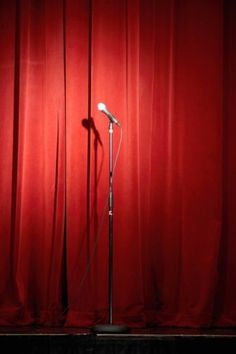 a microphone on stage with red curtains in the background