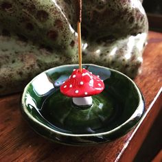 a small red mushroom sitting on top of a green bowl