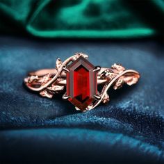 a red stone ring sitting on top of a blue velvet