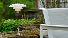 a lamp sitting on top of a rock next to a white chair