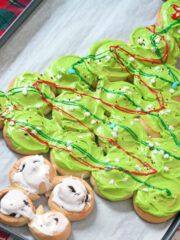 green frosted cookies with white icing and sprinkles are on a table