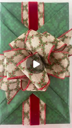 an ornament wrapped in green and red paper with a bow on it's side