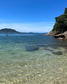 the water is crystal clear and there are some rocks in the foreground with an island in the distance