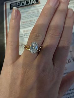 a close up of a person's hand with a diamond ring on their finger