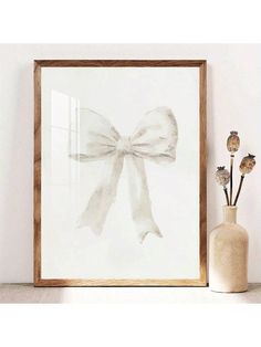 a white bow is hanging on the wall next to a vase