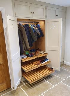 an open closet with clothes and shoes on shelves next to a white door in a room