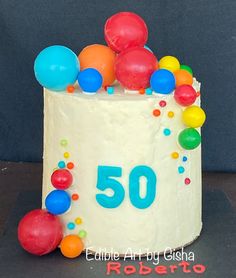 a birthday cake with the number 50 on it and balloons all around it in white frosting