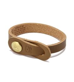 a brown leather bracelet with a gold button on the clasp and an inscription engraved on it