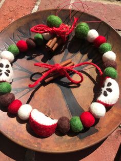 a wreath made out of felt and yarn on top of a wooden wheel with cinnamon sticks