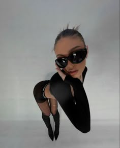 a woman in black is posing with her hands on her face and legs up to the side