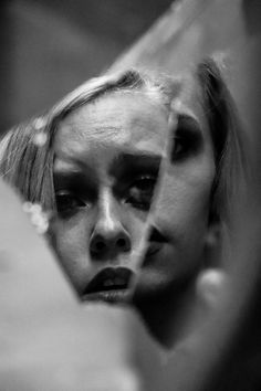 black and white photograph of a woman's face through a mirror with her hair blowing in the wind