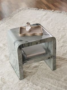 a marble side table with a tray on top and a white rug in the background