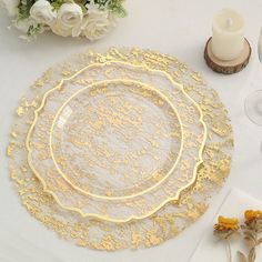 a table topped with plates and flowers on top of a white table cloth covered in gold foil